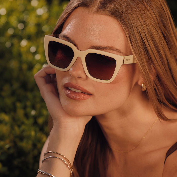 lifestyle - female wearing diff eyewear featuring the amara square sunglasses with a courtside ivory outside with gilded tortoise inside the frame and brown gradient polarized lenses detailed view