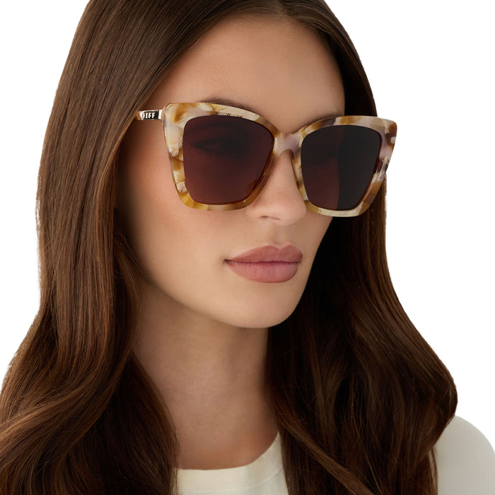 on model - female wearing diff eyewear becky ii cat eye sunglasses with a gilded tortoise acetate frame and brown gradient lenses angled view