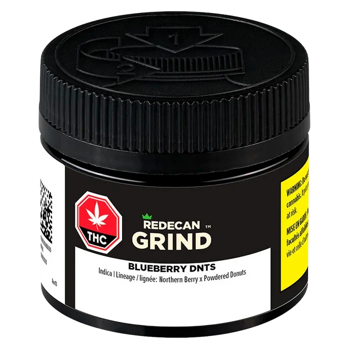 Close-up front view of a black jar labeled "Blueberry DNTs Grind" by Redecan Grind, showing textured screw-top lid and warning labels.
