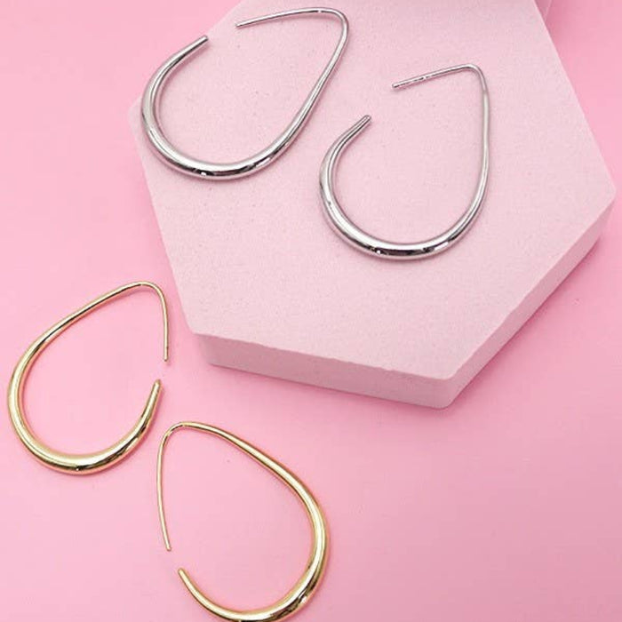 Pair of gold hoop earrings on a pink background