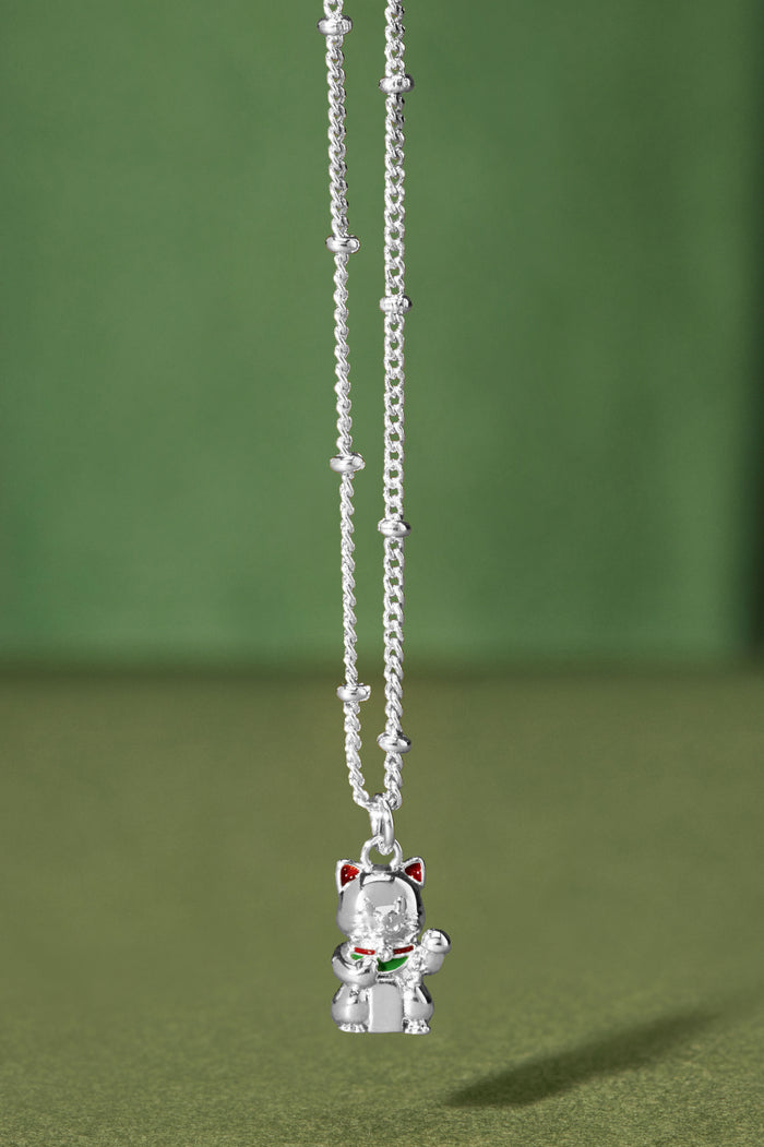 Silver cat-shaped pendant necklace on a green background