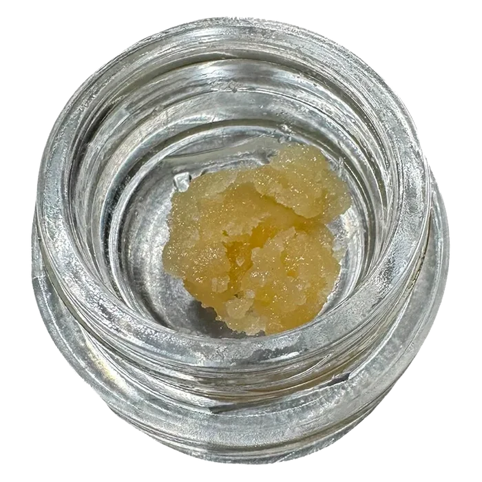 Top-down view of a pale yellow crumble inside a clear glass jar labeled Bane Chamber Wax.