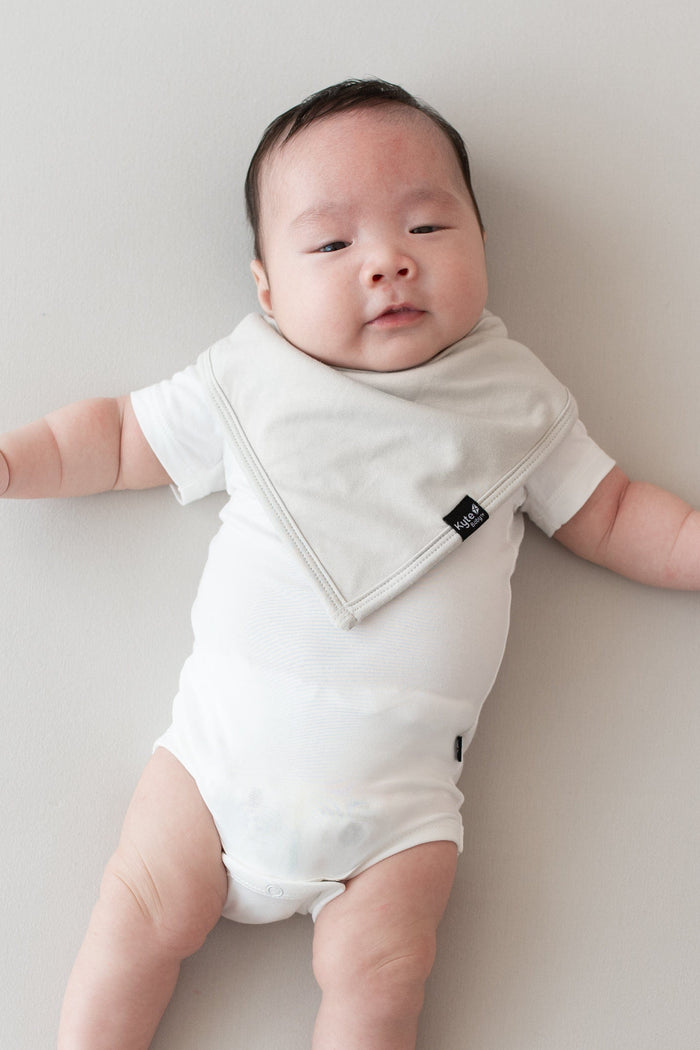Baby wearing a Bib in Oat and Short Sleeve Bodysuit in Cloud