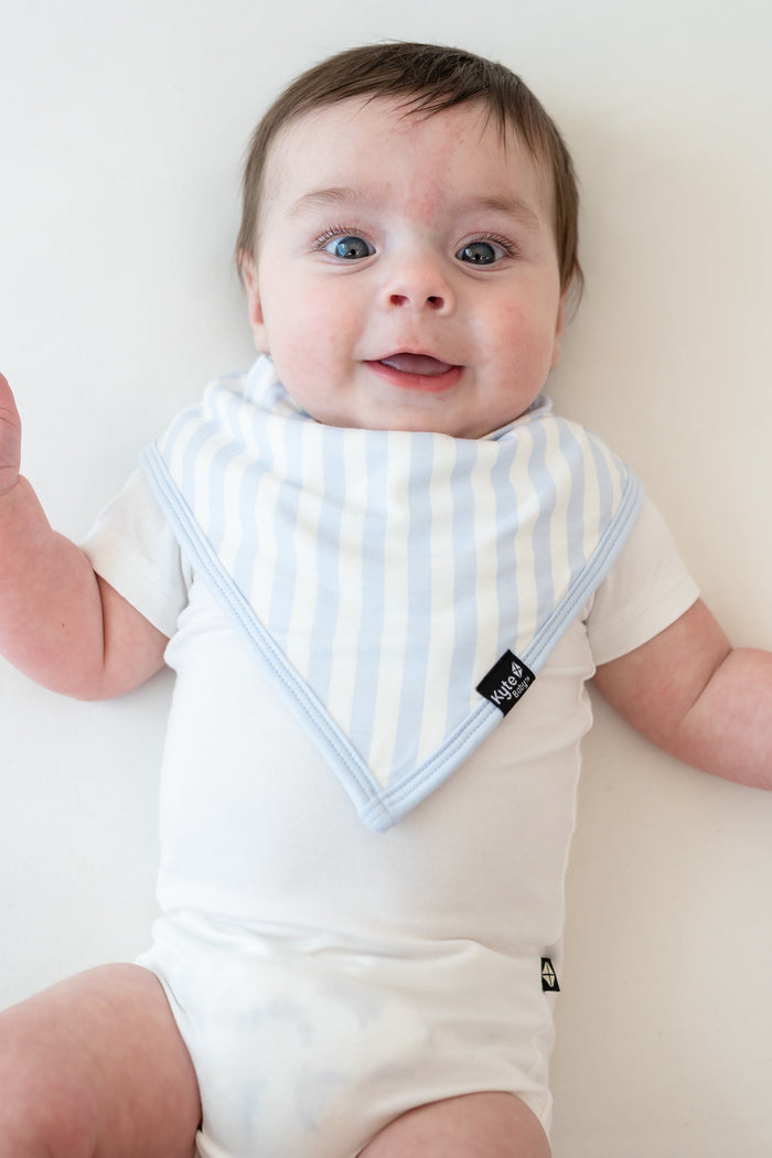 Smiling infant wearing the Bib in Big Mist Stripe paired with a Cloud Short Sleeve Bodysuit