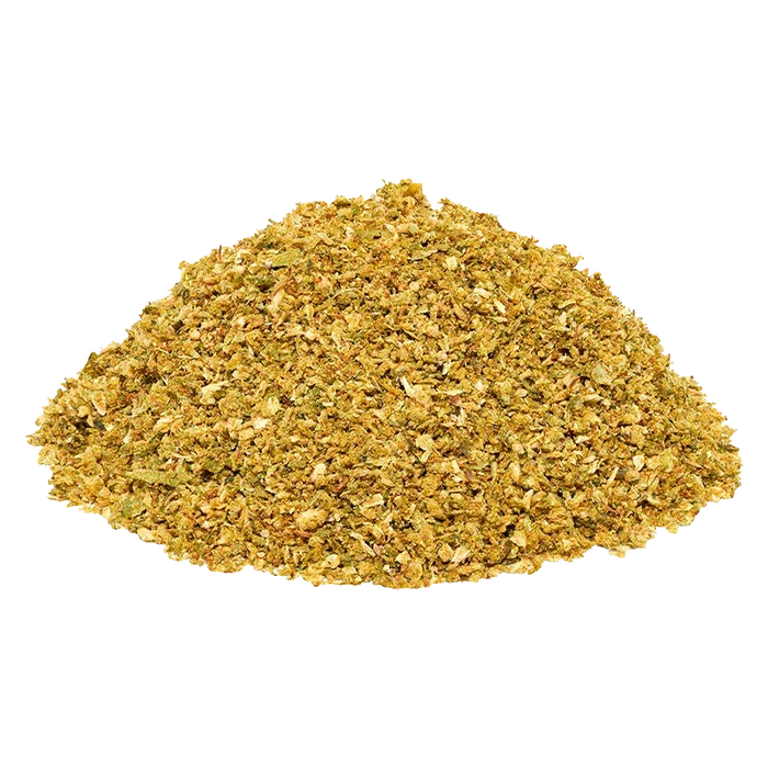Close-up of a mound of golden-green Blueberry DNTs Grind on a white background, showing coarse, flaky texture and mixed leaf pieces.