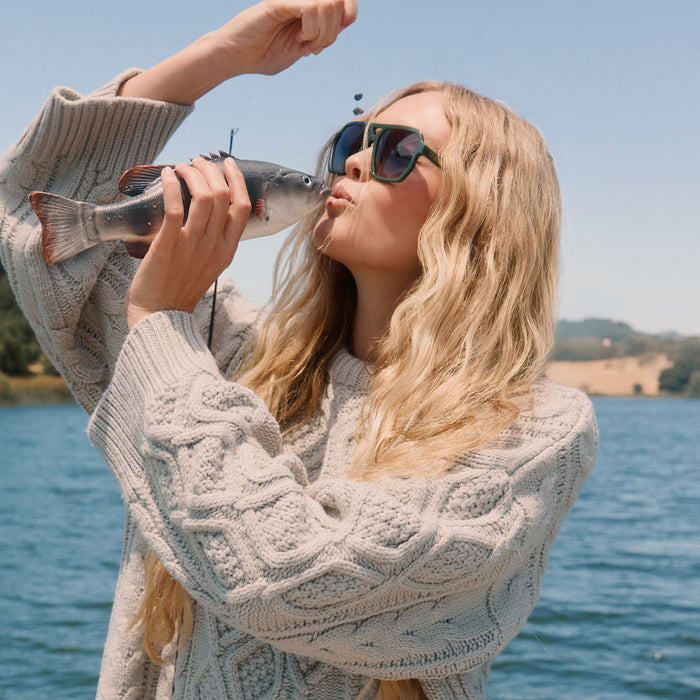 lifestyle -  blonde female fishing wearing diff eyewear featuring the cameron navigator sunglasses with a fairway green acetate frame and grey gradient polarized lenses angled view
