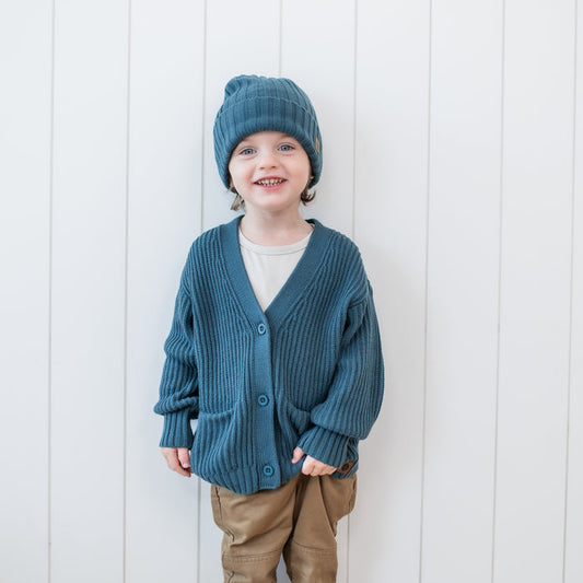 Young boy wearing the Chunky Knit Oversized Cardigan in Atlantic with matching Chunky knit Beanie