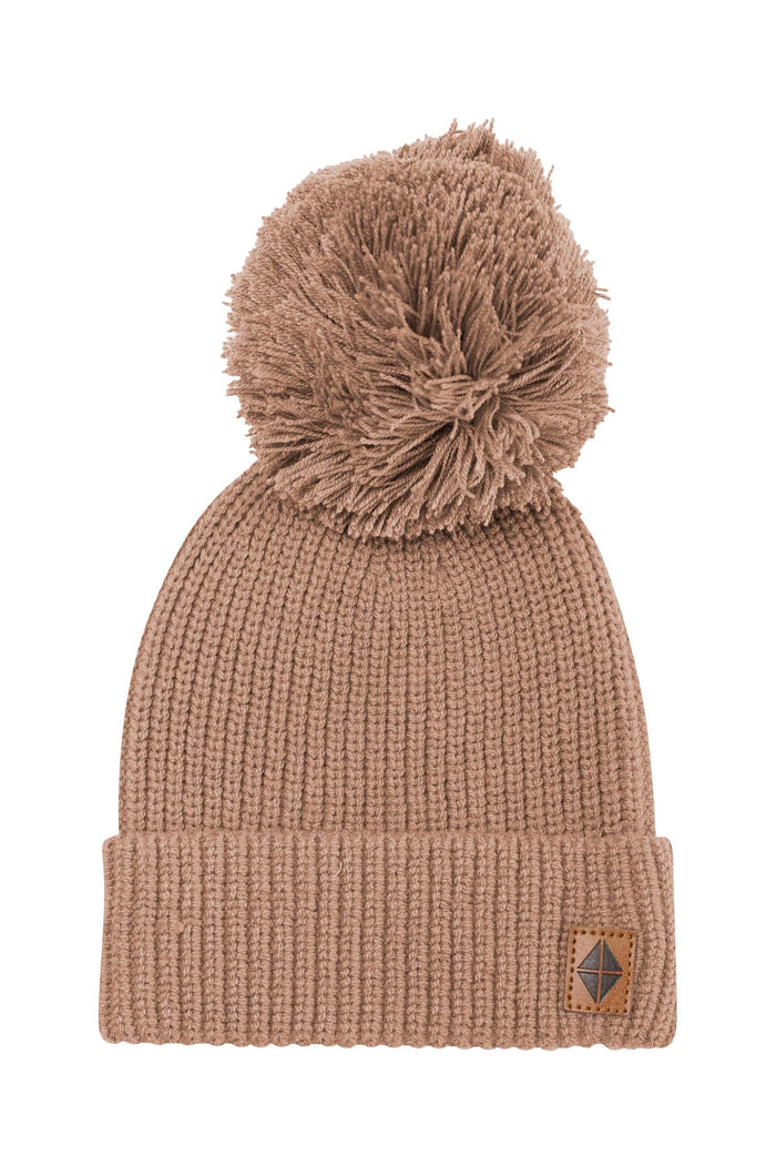 Product photo of the Chunky Knit Pom Beanie in Latte with the Kyte Baby vegan leather tag visible