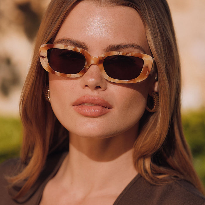 lifestyle - female wearing diff eyewear featuring the daphne rectangle sunglasses with a gilded tortoise outside and courtside ivory white inside acetate frame and brown polarized lenses front view