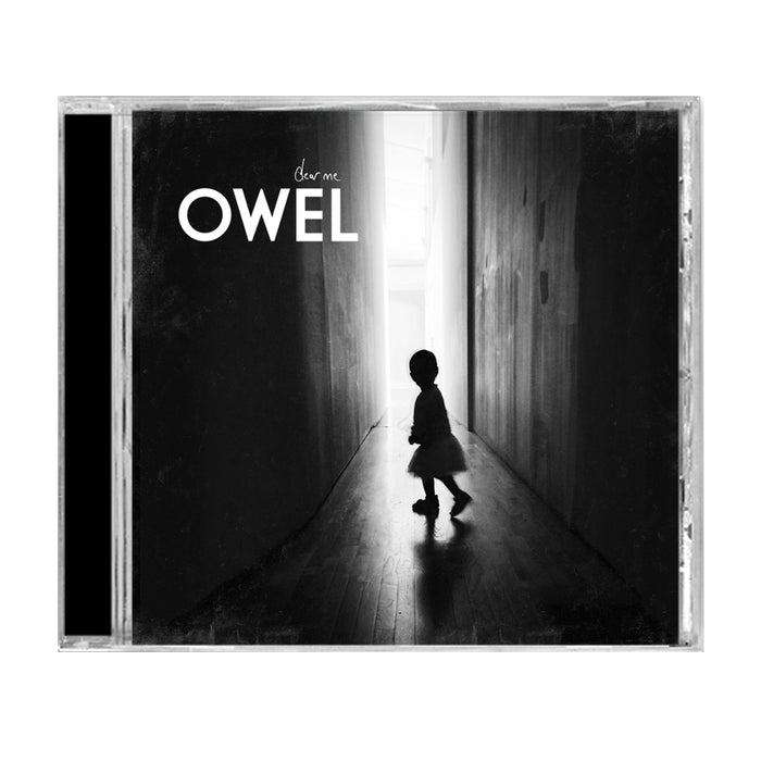 Black and white CD cover for OWELs Dear Me shows a child’s silhouette walking toward bright light in a dark hallway. Title and band name appear at the top; includes full Dear Me track list details.