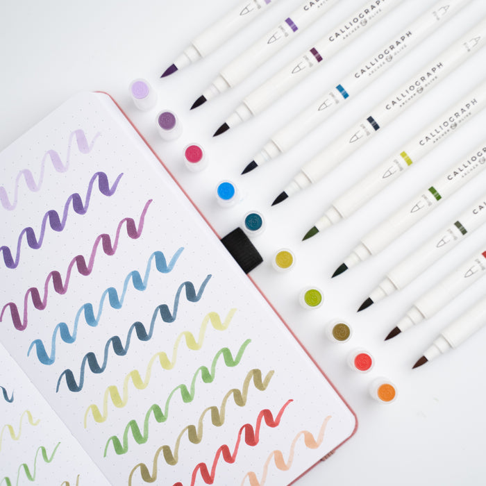 Set of Calligraphy markers with a sample of colorful calligraphy on paper