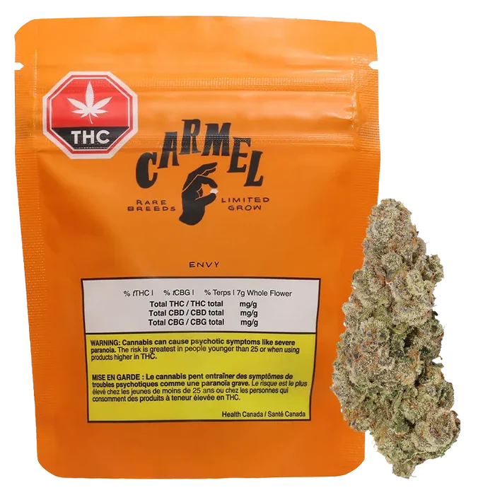 Front view of the orange Carmel Envy pouch with THC label, showing printed nutrition box and a cannabis bud beside it.