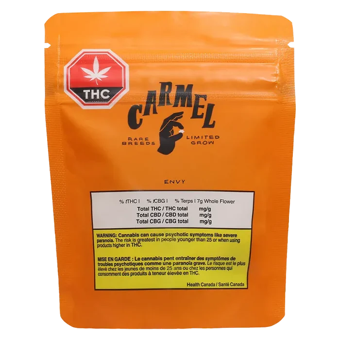 Front-facing shot of the orange Carmel Envy pouch with a black logo, THC symbol sticker, and warning panel visible.