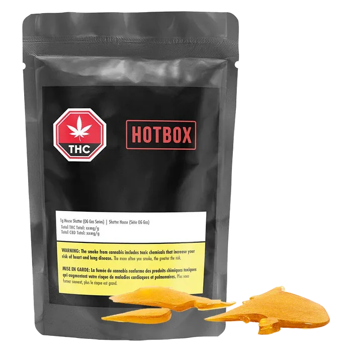 Front-facing shot of the black pouch labeled Hotbox House Shatter with a red THC badge and amber shatter pieces arranged at its base.