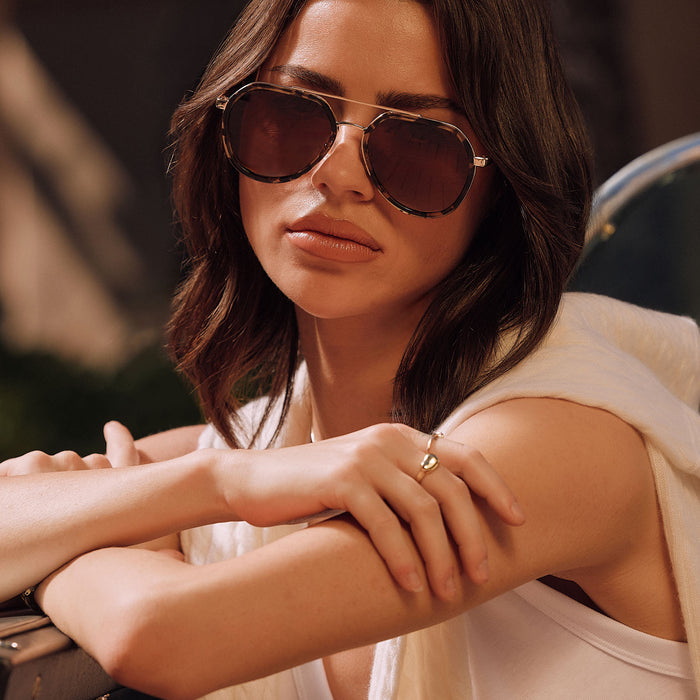 lifestyle - female outdoors wearing diff eyewear featuring the joey round sunglasses with a espresso tort & gold metal frame with brown gradient polarized lenses front view