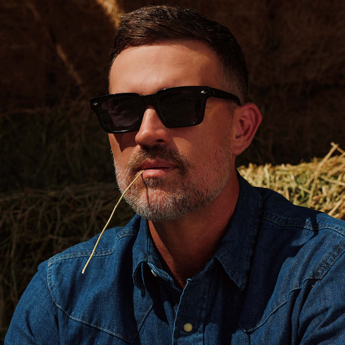 lifestyle - male cowboy wearing yellowstone x diff eyewear featuring the kayce dutton square sunglasses with a classic black acetate frame and grey polarized lenses front view