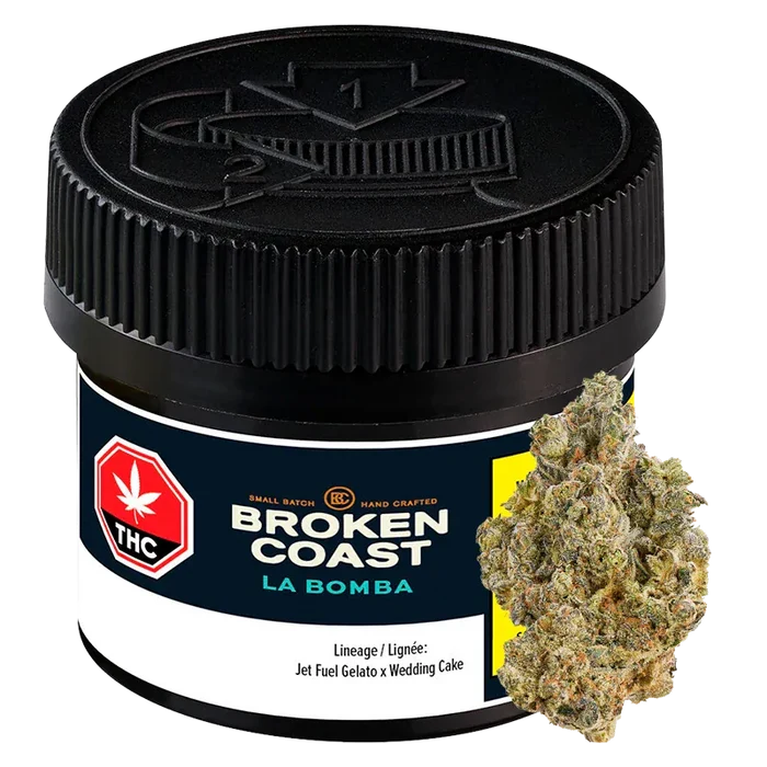 Front three-quarter view of the black-lidded Broken Coast La Bomba jar with label details visible and a cannabis bud leaning against its right side