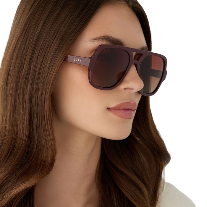on model - female wearing diff eyewear featuring the layton navigator sunglasses with a rugby red acetate frame and brown gradient polarized lenses angled view