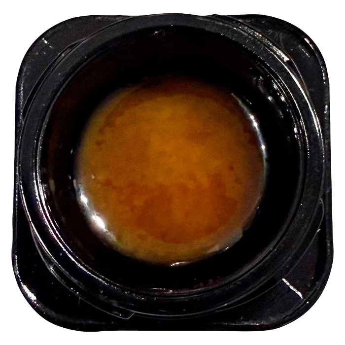 Top-down close-up of a glossy amber concentrate inside its black plastic jar labeled Live Rosin Reserve.