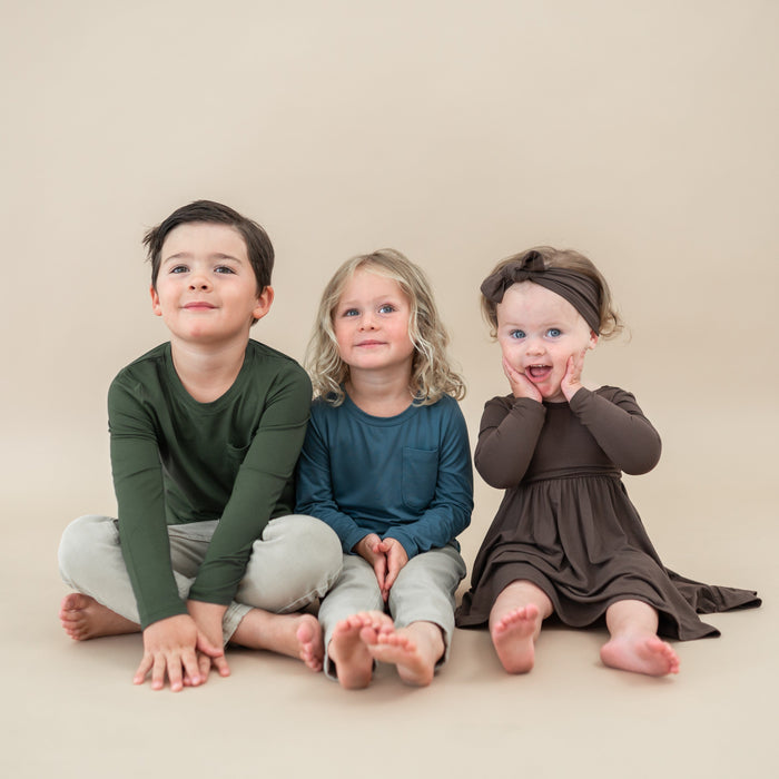 Child group photo of fall colors. Pictured is the Long Sleeve Twirl Dress in Espresso, Atlantic long sleeve crew neck and Fir long sleeve crew neck