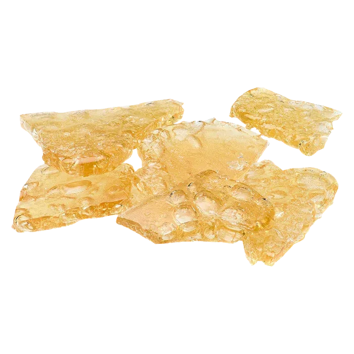 Close-up top-down view of amber, glassy shatter pieces labeled Mango Kush x Galactic Giggles Shatter scattered on a white background