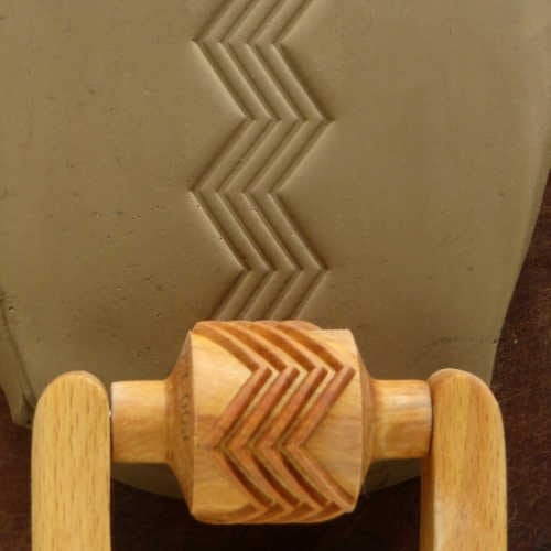 MKM Medium Handle Roller in the 4Zag pattern, four nested zigzag lines rolled into grey clay