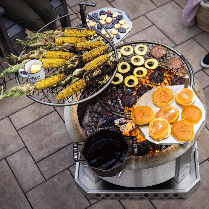This is a photo of an X30 Firepit with two Outposts attachments, used for grilling corn, burgers and other veggies.