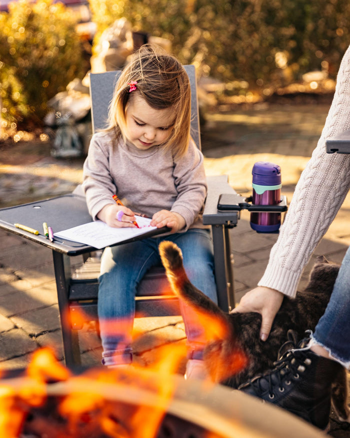 A image of a child coloring on an X Series kids chair with attached Outrig Tray Table and Outrig Cupholder