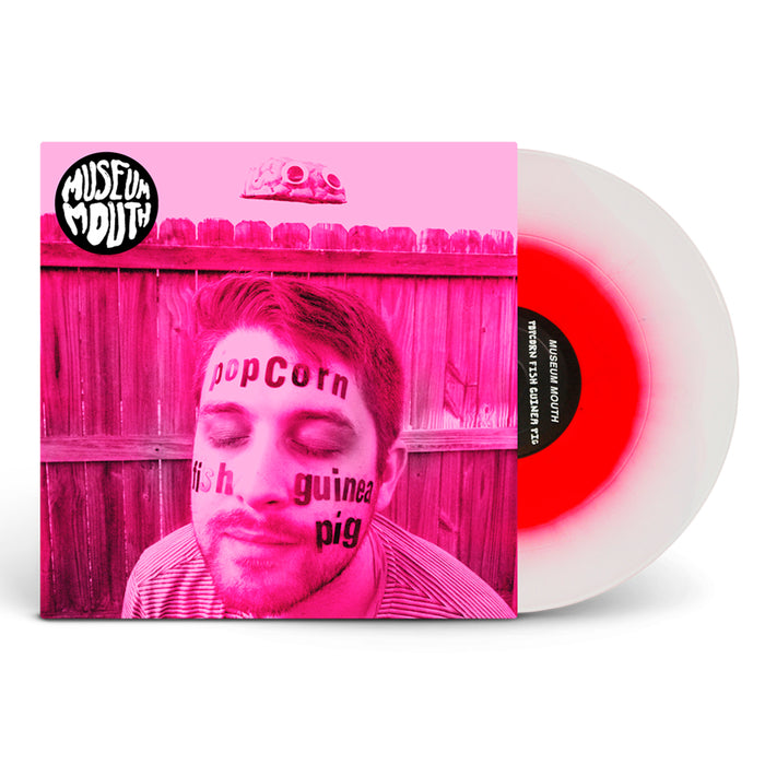 Museum Mouth Popcorn Fish Guinea Pig LP album cover shows a pink-tinted man with "Popcorn Fish Guinea Pig" on his face, a UFO over a fence, and includes white vinyl. Unique limited pressing for collectors.