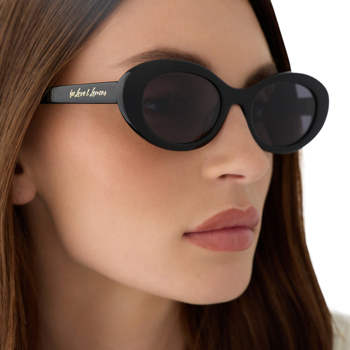 on model - female wearing for love & lemons x diff eyewear featuring the sabrina oval sunglasses with a black acetate frame and grey polarized lenses detailed view