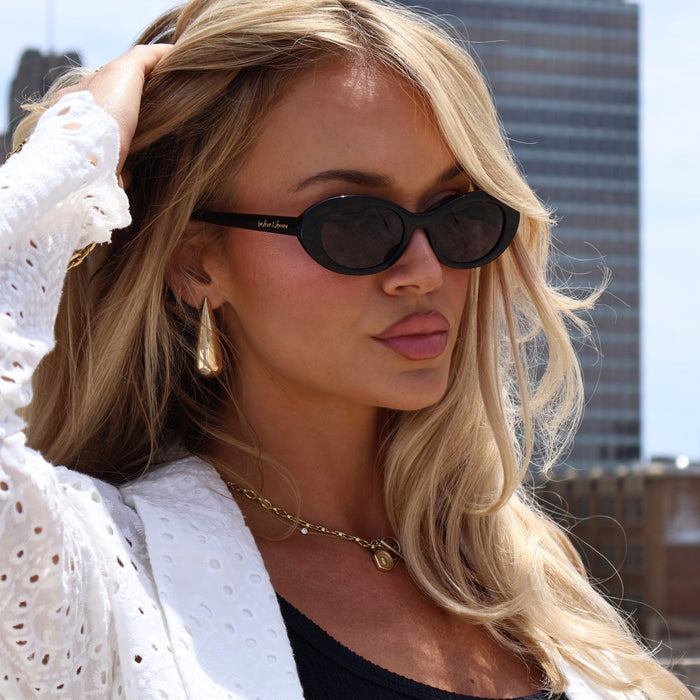 ashley smith wearing black oval sunglasses on roof top with gold accessories