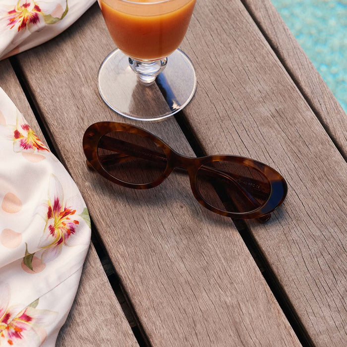 still life - diff eyewear x for love and lemons sabrina sungalsses in tortoise laying next to a pool