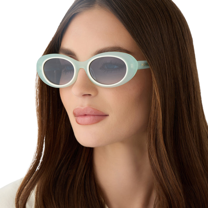 on model - female wearing for love & lemons x diff eyewear featuring the sabrina oval sunglasses with a pastel sage acetate frame and blue gradient lenses angled view