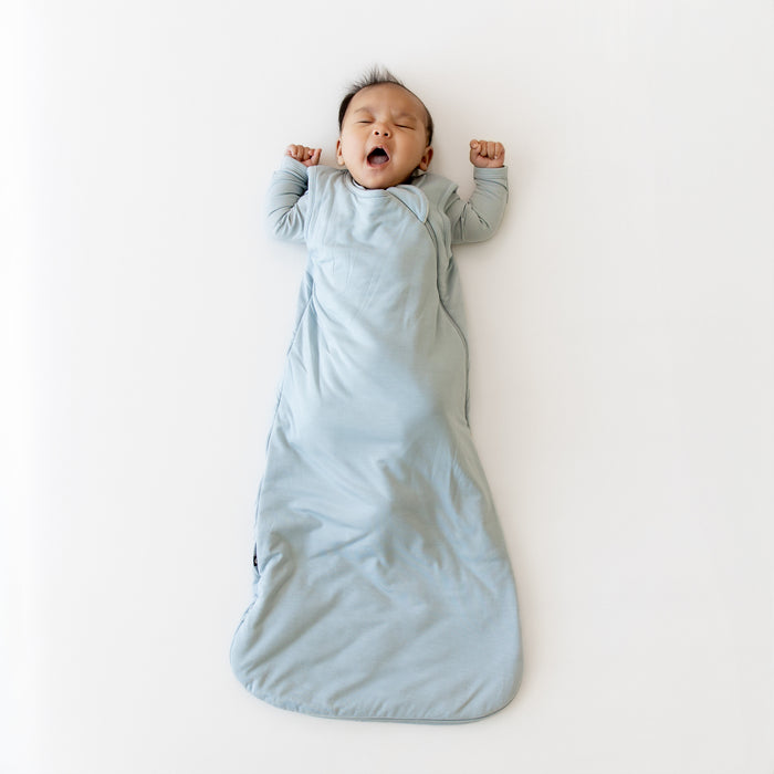 Baby yawning in a light blue sleep bag