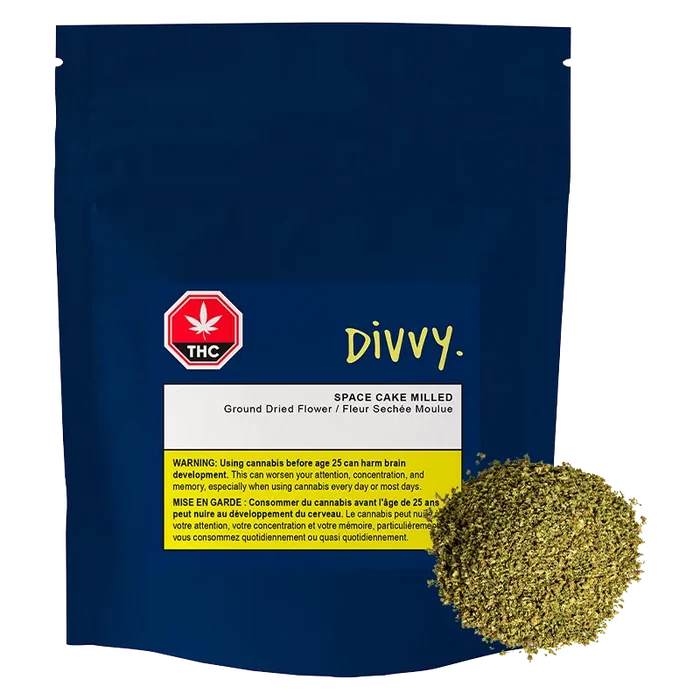 Front view of the navy pouch labeled "DIVVY. SPACE CAKE MILLED" with a white and yellow warning panel and a mound of milled herb at the lower right.