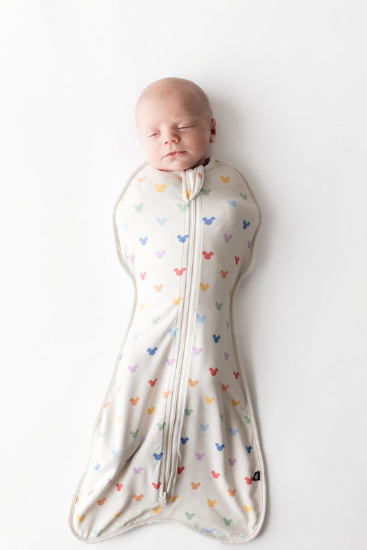 Baby asleep in kyte baby swaddle bag with pastel mickey head pattern