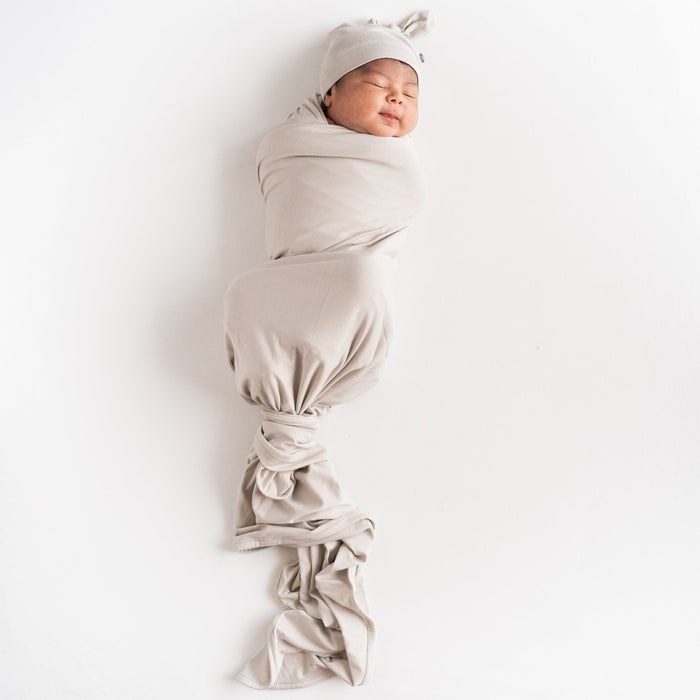 Newborn swaddled in Kyte Baby Swaddle Blanket in Oat