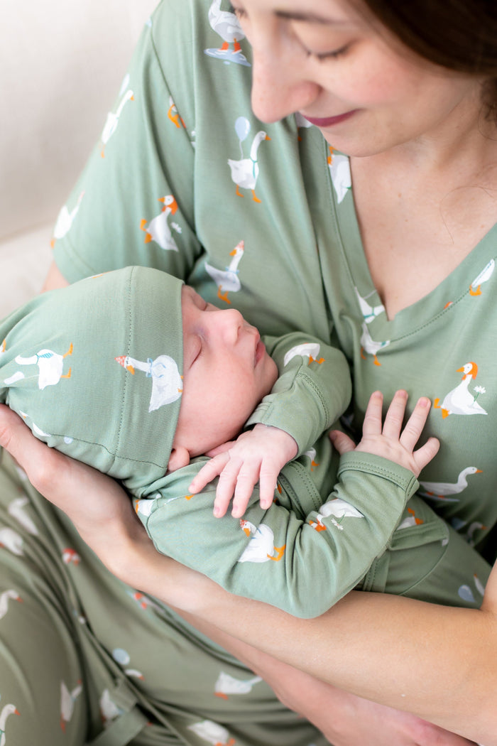 Close up of mother holding sleeping newborn wearing the Take Me Home Set in Silly Goose