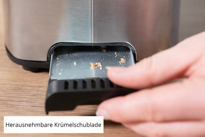 Eine Hand entfernt die Krümelschublade aus dem Unold Toaster Tom und gibt darin einige Krümel frei. Der deutsche Ausdruck „Herausnehmbare Krümelschublade“ bedeutet „herausnehmbare Krümelschublade“.