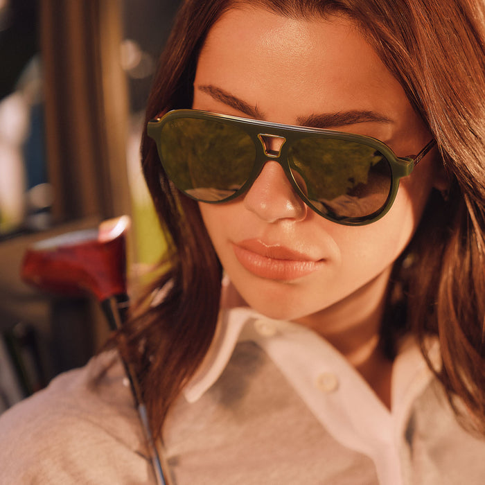 lifestyle - female lookinig down wearing diff eyewear featuring the tosca iii aviator sunglasses with a fairway green acetate with gold accentsframe  and aloe green gradient w/ light gold flash lenses