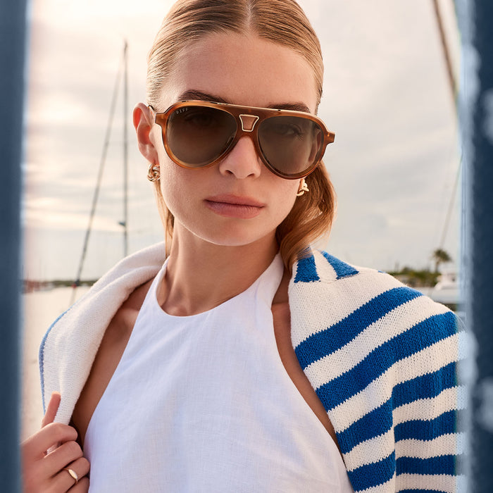 lifestyle - female on a boat wearing diff eyewear tosca iii aviator sunglasses with a tawny brown tortoise frame and brown gradient polarized lenses