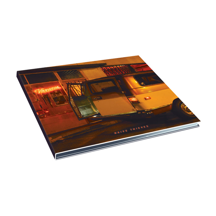 An album cover for Naive Thieves shows a yellow van with its door open, glowing inside, parked by a neon-lit building in Shakedowntown. Warm streetlights brighten the scene, with Naive Thieves visible on the cover.