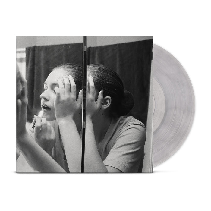 Black and white photo of a woman applying lipstick at a mirrored cabinet. Her reflection and the translucent Lume vinyl from this limited LP pressing are visible, featured as the cover art for Lumes Wrung Out album.