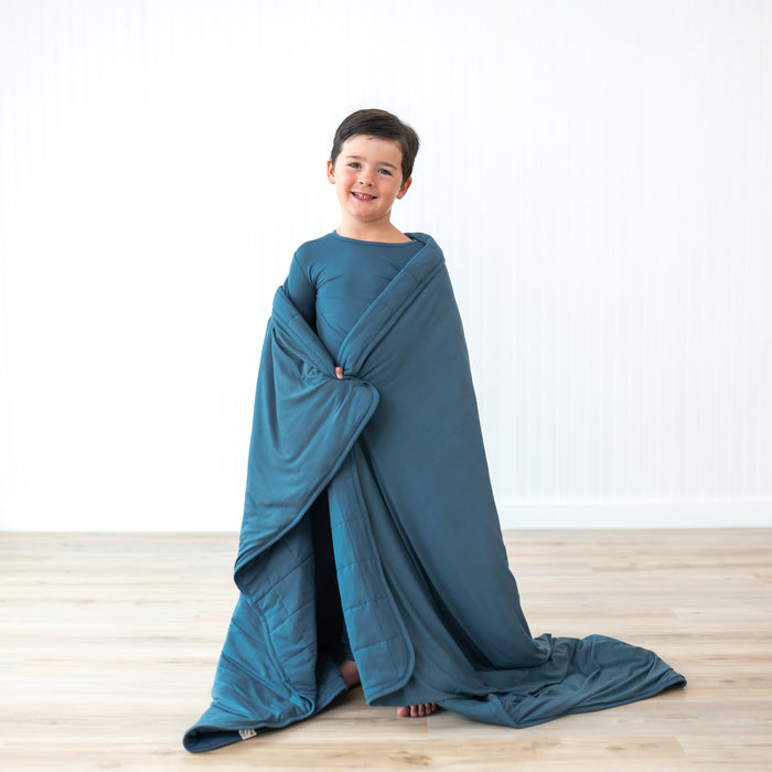 Child wearing bamboo kids pajamas and wrapped in Youth Blue Blanket in Atlantic 2.5