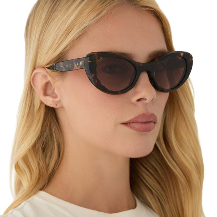 on model - female wearing diff eyewear featuring the zaria cat eye sunglasses with a espresso tortoise frame and brown gradient lenses angled view